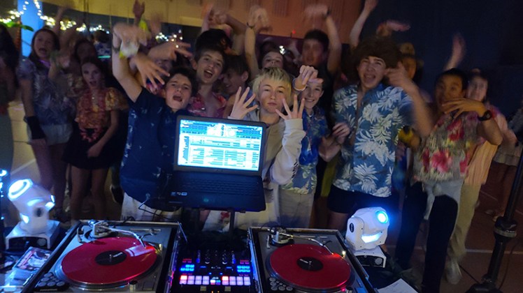 Saint Ann's Middle School Hawaiian Luau Themed dance party with Denver's Best DJs. A bunch of kids having a great time in their Hawaiian shirts and leis in front of DJ Emir's Turntables.